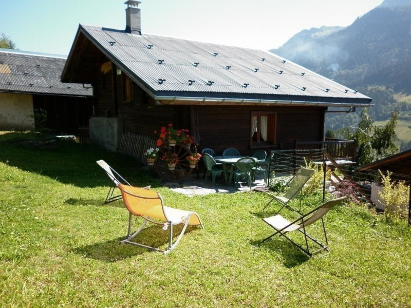 chalet entouré de prairie,non cloturé. terrasse avec table, chaises,parasol et chaises longues